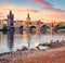 White swans on the shore of Vltava river. Superb summer sunrise on  Prague with Charles bridge Karluv Most on background