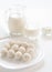 White sweet coconut truffles on a plate, milk glass and jug, cottage cheese in a bowl at defocused background.