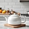 A white table with a Bauhaus teapot rests against a traditional kitchen backdrop