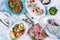 White table with different food, salads and snacks, plates and napkins