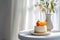 On the white table, there is a vase on the right, Small cake, orange,with a blurred background in a Nordic style, minimalist AI