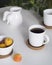on white table, white cup with black coffee stands on brown round stand. second cup is in back out of focus. in upper