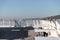 White tables on a sunlit wooden pier.