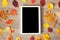 White tablet on a wooden table with colorful autumn leaves, business concept with space for text, advertising, and for any other