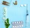 White tablets, glass ampoules, a syringe and cherry blossoms are arranged on a light blue background.