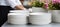 White tableware close up with woman washing dishes in bright kitchen, blurred background, text space