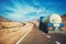 White tanker and trucks driving along picturesque desert mountain highway.