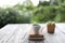 White teacup with leather book and silver pencil and small succulent plant on wooden table