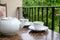 White teapot and cup of tea on table. Outdoor breakfast on balcony cafe