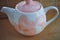 White teapot with pink hearts on a background of a bomb