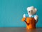 The white teddy bear sitting in orange watering cans put on wooden table. the background is turquoise and copy space for content