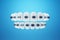 White teeth with metal braces on a blue background. Dental braces, orthodontic treatment, dentistry, teeth whitening, protection,