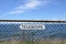 White telescope sign on metal fence and ocean