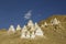 A white temples Buddhist stupas on the slope of a desert mountain under a blue sky with white clouds