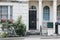 White terraced house with black entrance door on a street in London, UK