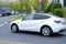 white Tesla car turning crossroads, electric vehicle in European city, energy lithium-ion 4680 battery, alternative energy