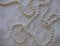 White textured background of lustrous pearls on a rich patterned fabric