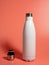 White Thermal bottle on a pink background. Thermos bottle