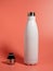 White Thermal bottle on a pink background. Thermos bottle