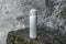 White thermos of tea or coffee on stone near waterfall with splashes of water drops. Adventure hiking tourism concept