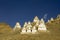 A White Tibetan Buddhist stupas on a deserted hillside against the blue sky and clouds. Buddhist holy temple