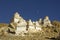 A white Tibetan Buddhist stupas temples on a deserted stone mountainside against the backdrop of a clean dark blue sky and moon