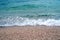 White tidal wave between turquoise seawater and pebble beach