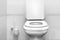 white toilet bowl close-up in a tiled toilet room minimalistic design