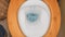 White toilet bowl in flat rest room. Closeup top view of a flushing white toilet. The blue water swirls in bowl