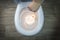 White toilet bowl on a wooden background. the hand lowers the lit firecracker. close-up