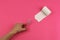 White toilet paper on pink background and human hand with scissors, close-up, copy space, concept of stomach problems