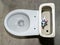 White toilet tank with an open lid and flush system. Plastic toilet drain system