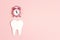 White tooth with alarm clock on pink background. Time to dental health. Dentist day concept