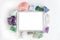 White touchpad with blank touchscreen framed by crystals and gemstones on a white background with blank space. Flat lay