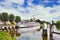 White tour-boat moored in a tranquil canal with a windmill on the background, Gouda, Netherlands