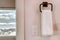 White towel hanging on square towel holder beside electrical rocker light switch
