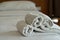 White towels roll on bed in hotel bedroom