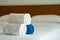 White towels roll up on bed in hotel bedroom