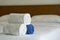 White towels roll up on bed in hotel bedroom