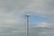 White tower wind turbine on cloudy sky.