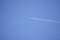 White trace of the plane against the blue sky without clouds. combustion of fuel in the aircraft, emissions. travel concept