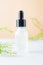 White transparent cosmetic bottle and pipette with drop of oil serum liquid essence on beige background, cosmetics laboratory,