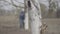 White tree trunk on spring day with blurred woman whitening plants at the background. Wide shot of unrecognizable female