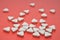 White triangular unusual pills dispersed on a pink background closeup