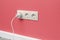 White triple outlet on pink wall
