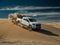 White truck driving down a sand dune