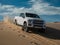 White truck driving down a sand dune