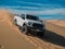 White truck driving down a sand dune