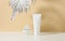 White tube for cosmetics, a jar of cream and silver leaf on a white table. Cosmetic on a beige shadow backgroun