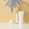 White tube for cosmetics, a jar of cream and silver leaf on a white table. Cosmetic on a beige shadow background. Cream bottle,
